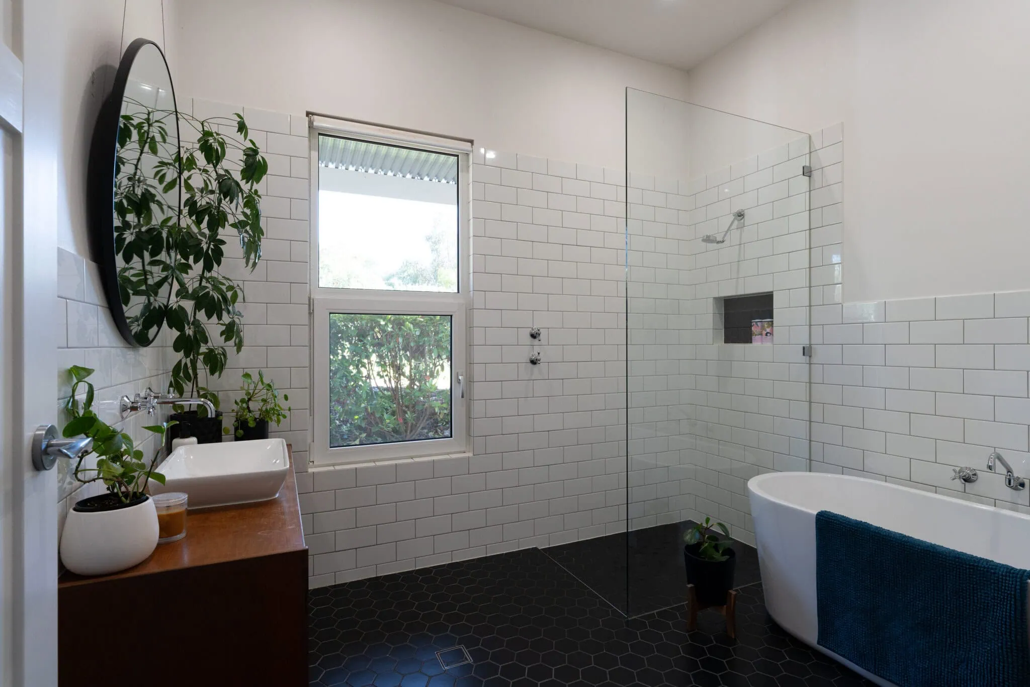 Contemporary bathroom with walk-in shower, bathtub, white subway tiles, and natural light.