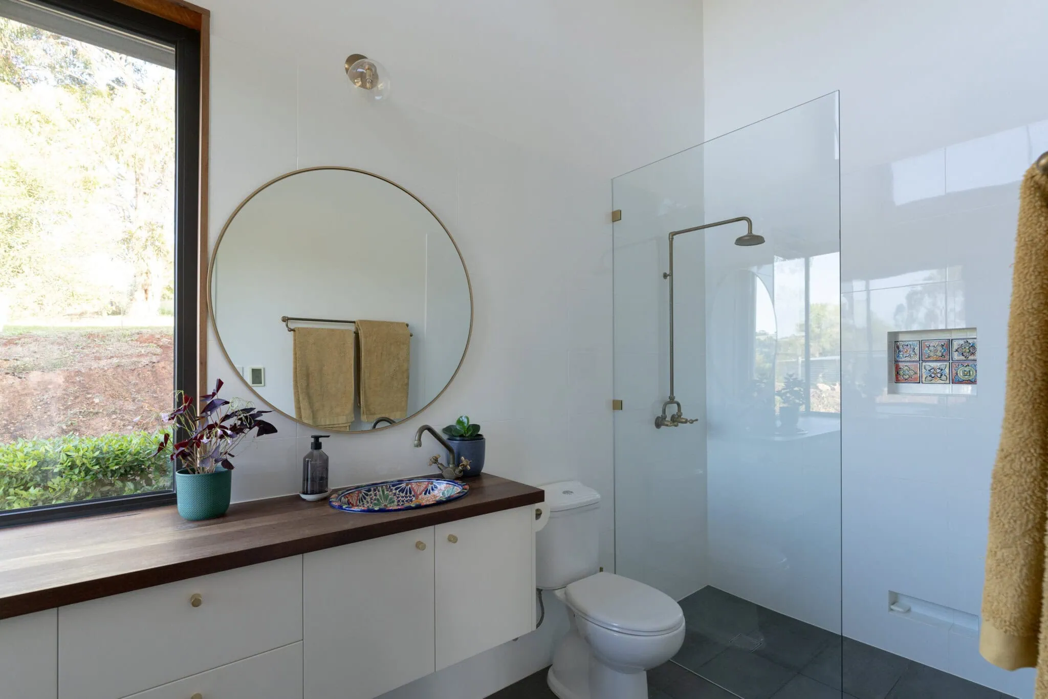 Bathroom with walk-in shower, toilet, and vanity with mirror and decor.