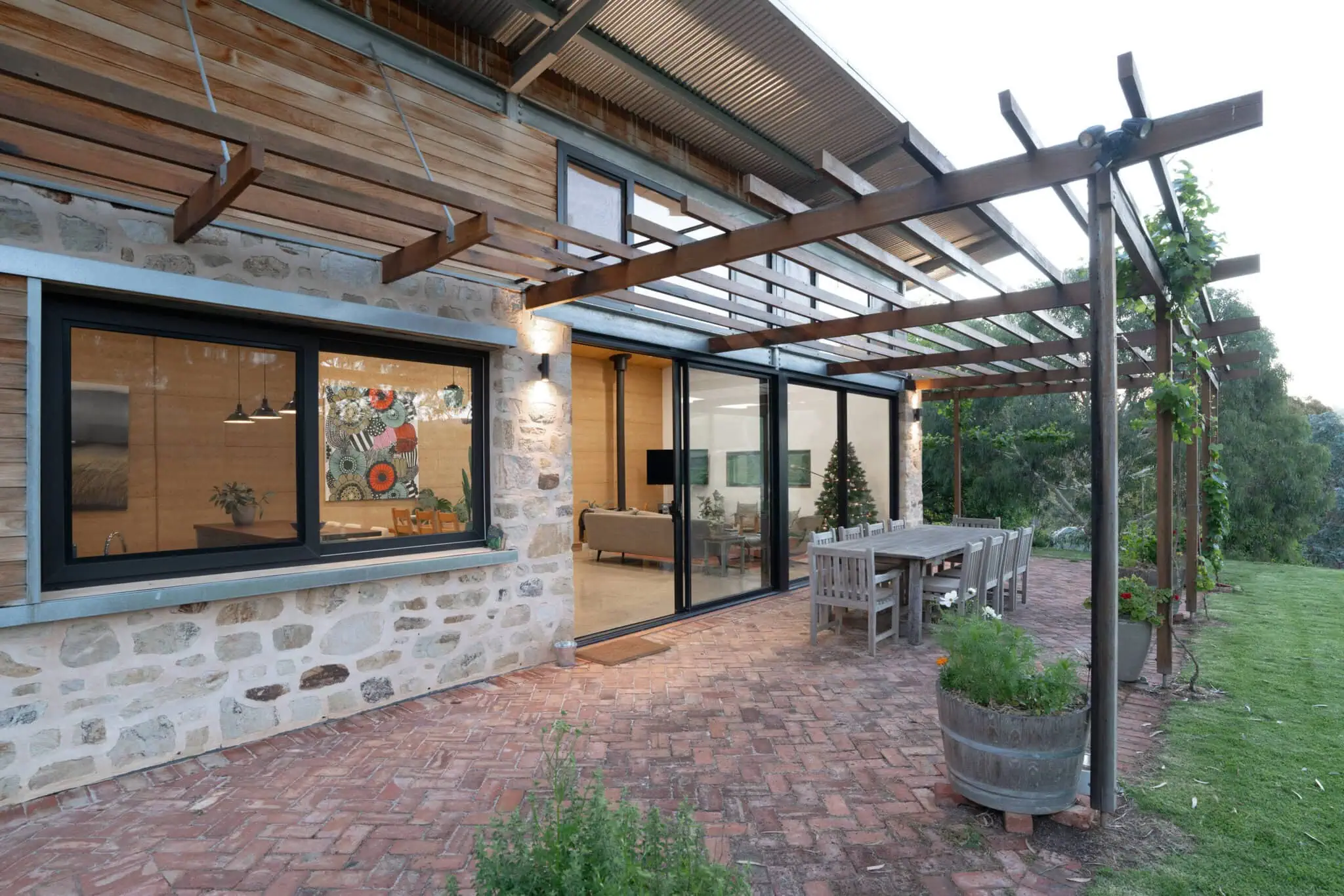 Modern outdoor living area with timber pergola, brick patio, and seamless indoor-outdoor connection.