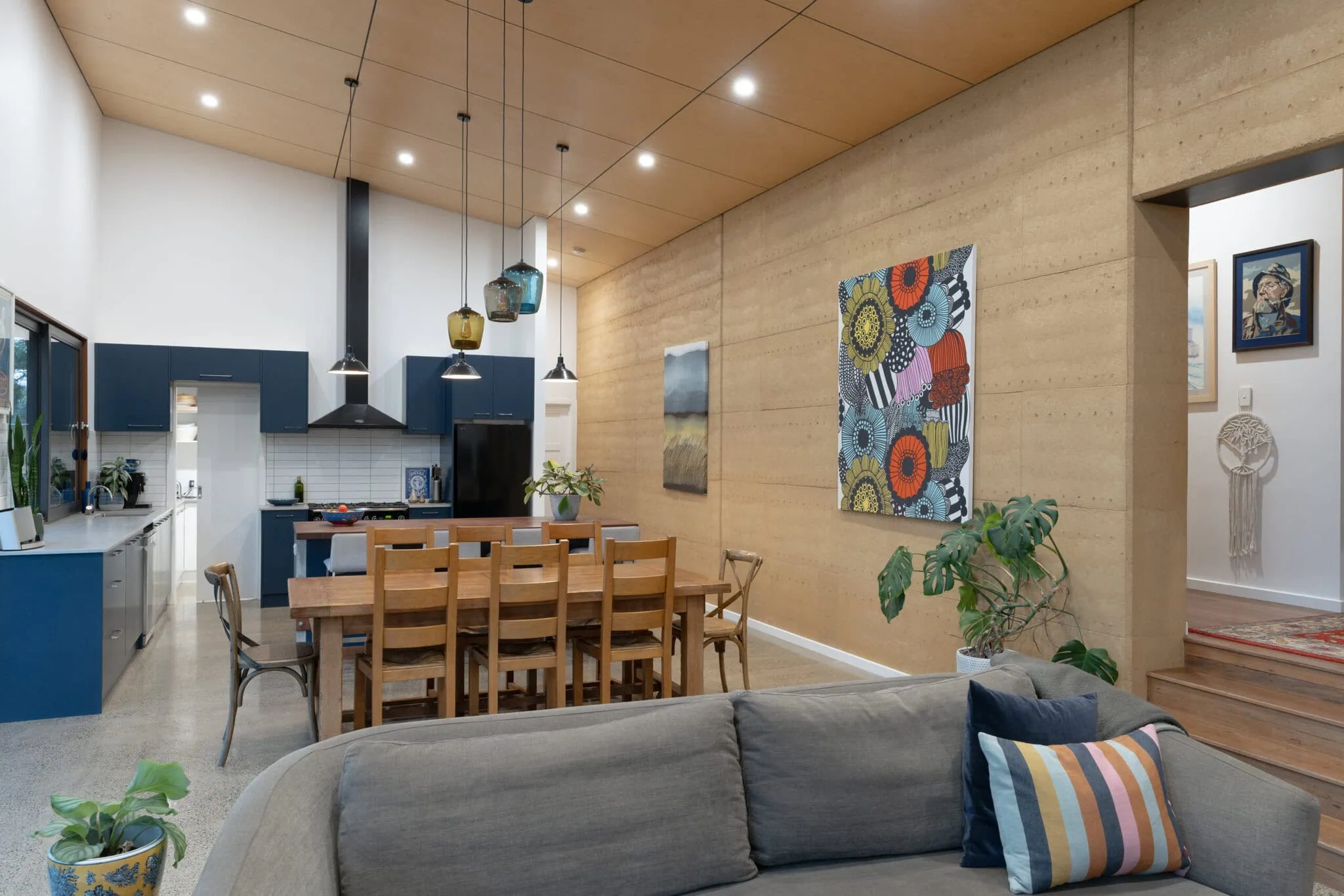 Bright open-plan kitchen and dining space with contemporary design, colourful artwork, and natural timber accents.