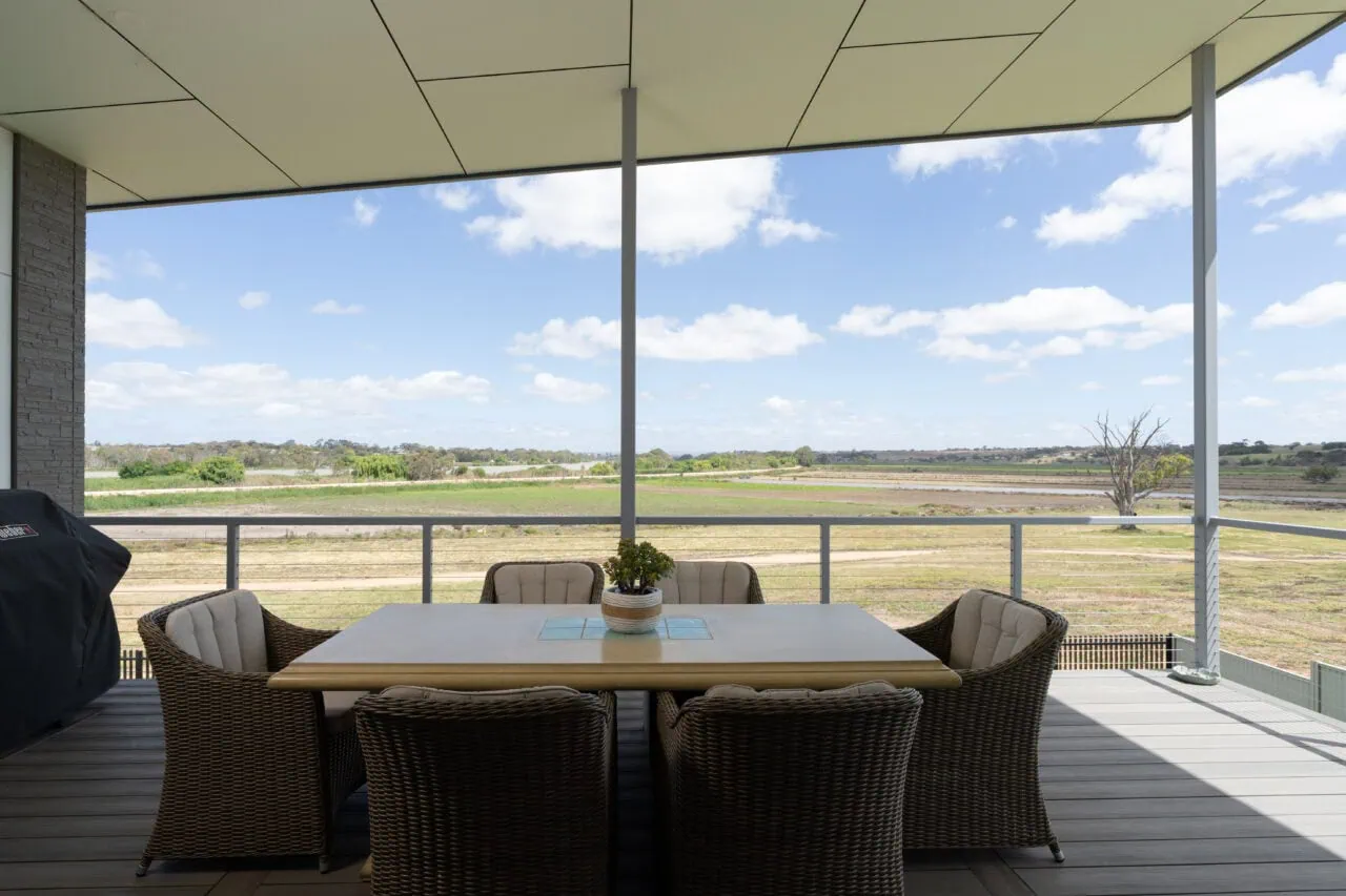 Outdoor balcony with rural landscape, timber decking, and stylish seating setup.