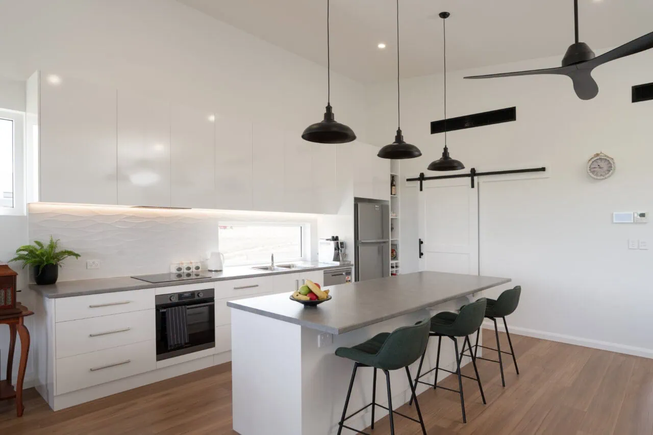 Bright modern kitchen with sleek white cabinets, island breakfast bar, and black pendant lighting.