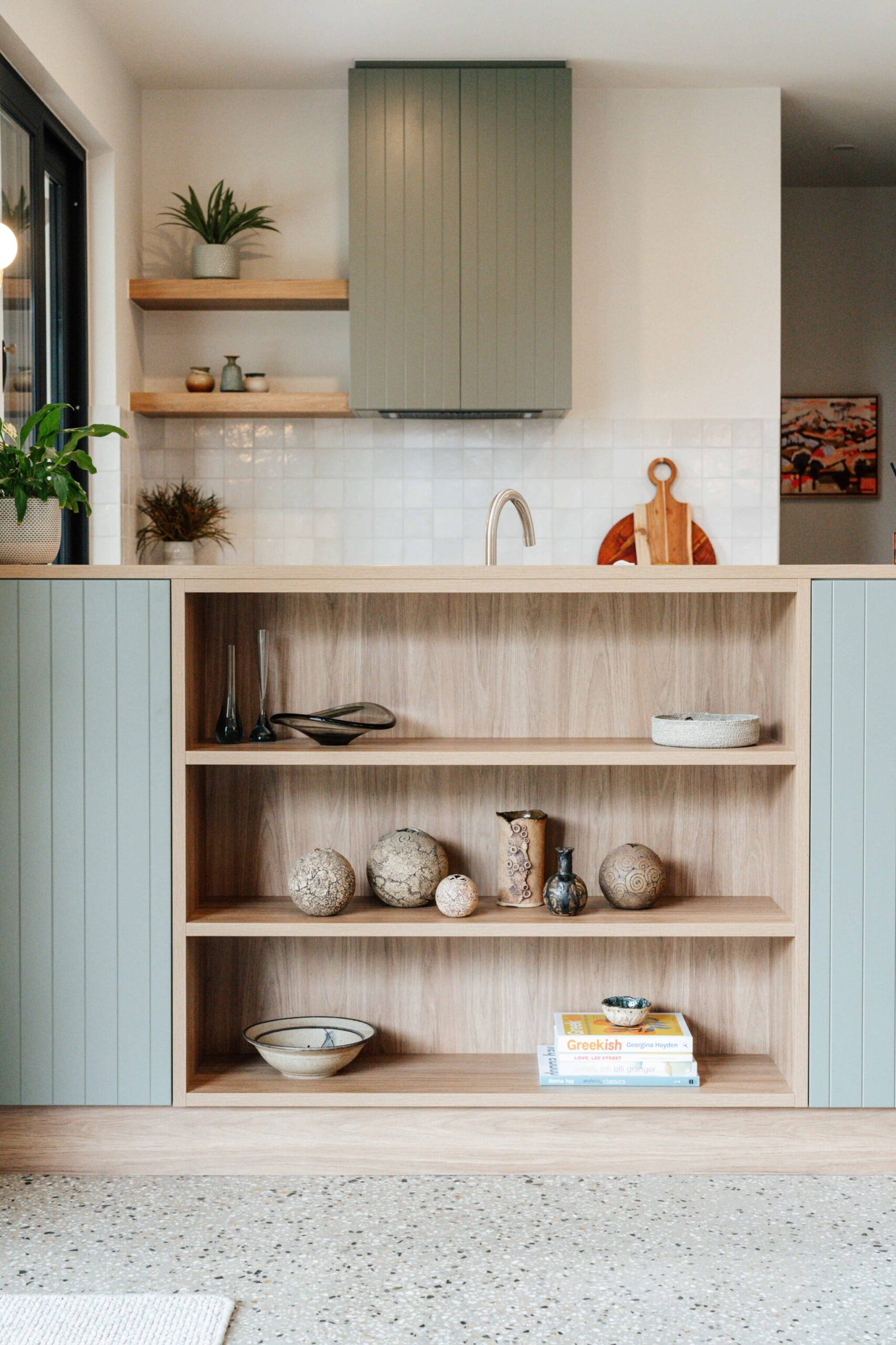 Open-plan kitchen featuring stylish cabinetry, natural wood accents, and decorative items for contem.