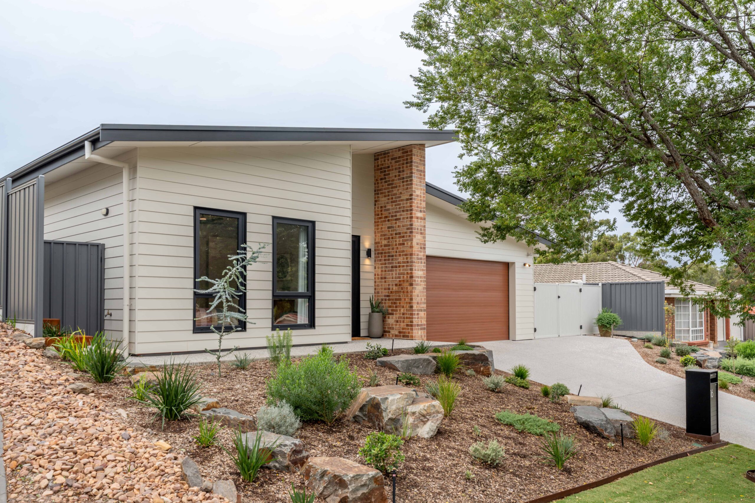Modern house with landscaped garden and garage in a suburban setting.
