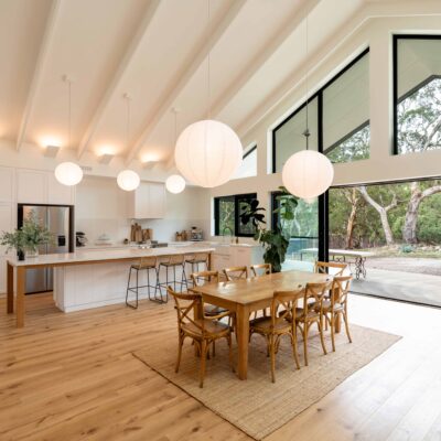 Spacious modern kitchen and dining space featuring large glass windows, wooden furniture, and contem.