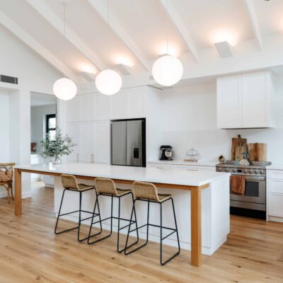 Bright, contemporary kitchen featuring white cabinets, a large island, and stylish pendant lighting.