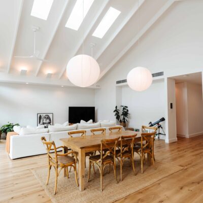 Bright modern dining room with skylights, white walls, and wooden furniture.