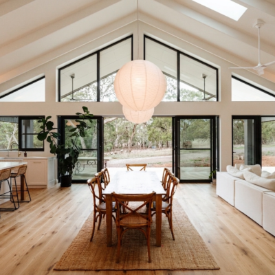 Spacious living room with high ceilings and large glass windows overlooking nature.