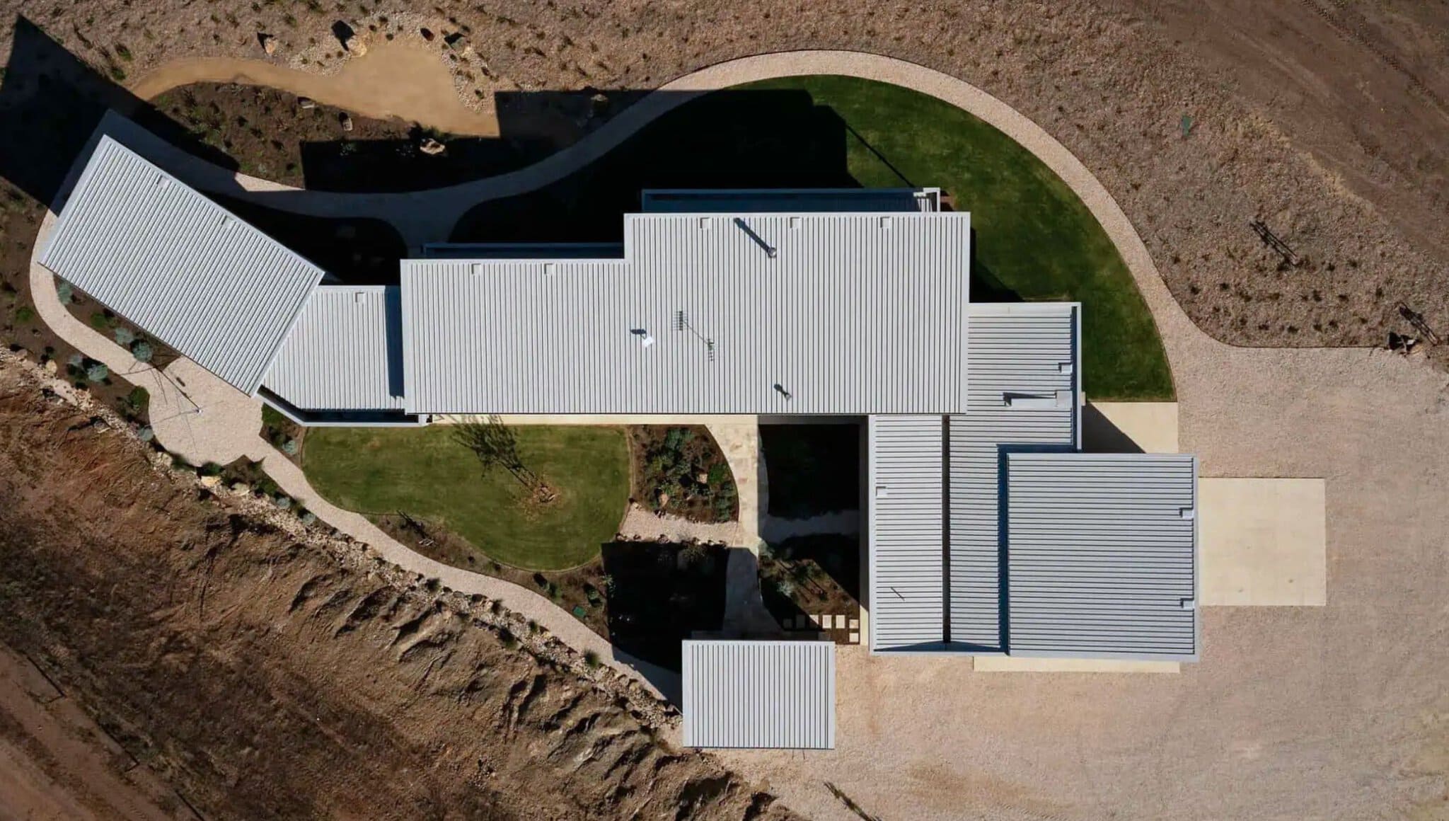 Aerial view of a contemporary Australian home with metal roofing and landscaped yard.
