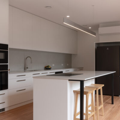 Contemporary kitchen with white cabinetry and island, part of Project West Beach.