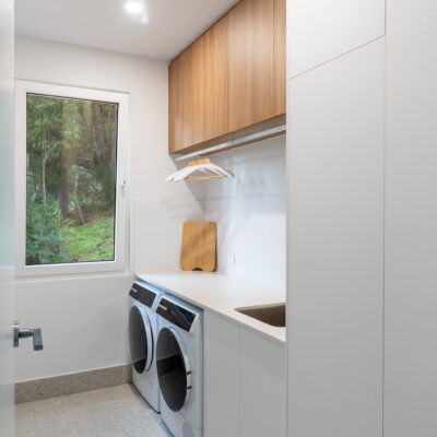 Contemporary laundry room with white cabinetry and wooden accents.
