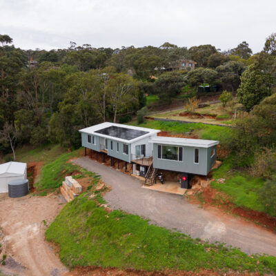 Contemporary modular home built on a hillside in Aberfoyle Park, surrounded by lush greenery.