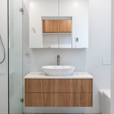 Contemporary bathroom with wooden and white cabinetry and vessel sink.