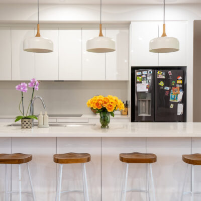 Contemporary kitchen with white cabinetry, island, and pendant lighting.