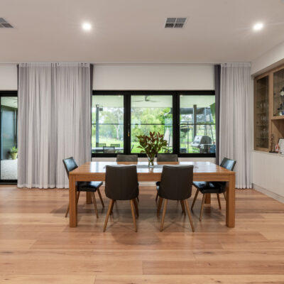 Spacious modern dining room with wooden table and black chairs, large windows, and built-in display.