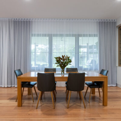 Contemporary dining room with wooden table and black chairs.