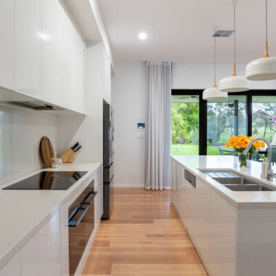 Contemporary kitchen with white cabinetry, island, and large windows for natural light.