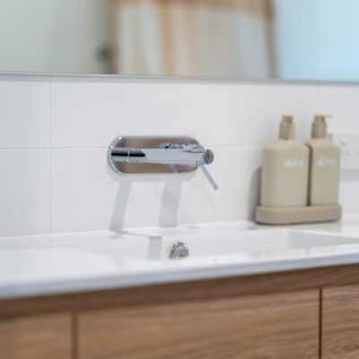Contemporary bathroom sink with wooden cabinet and wall-mounted faucet.