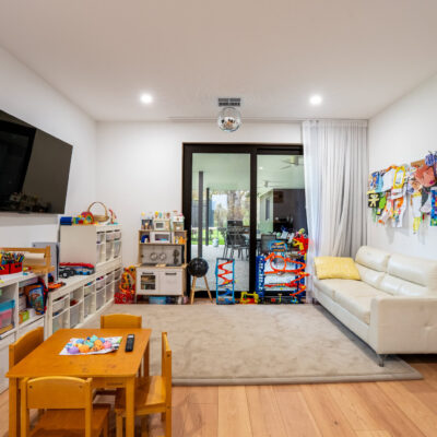 Modern living room with children's play area and sliding glass door.