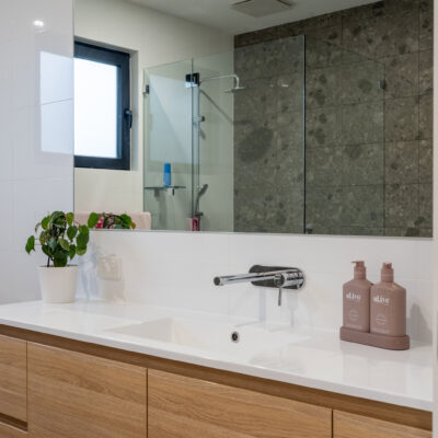 Contemporary bathroom with wooden vanity, large mirror, and walk-in shower.